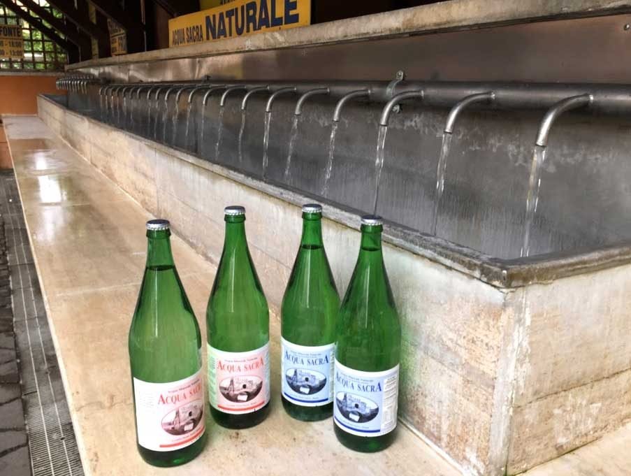 Acqua Sacra 3 Row of taps at the Acqua Sacra spring with glass bottles in the foreground